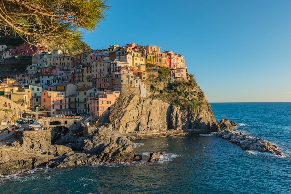 Cảnh quan bờ biển tuyệt đẹp của làng Manarola với những ngôi nhà đầy màu sắc trên vách đá nổi bật trên nền trời xanh trong.