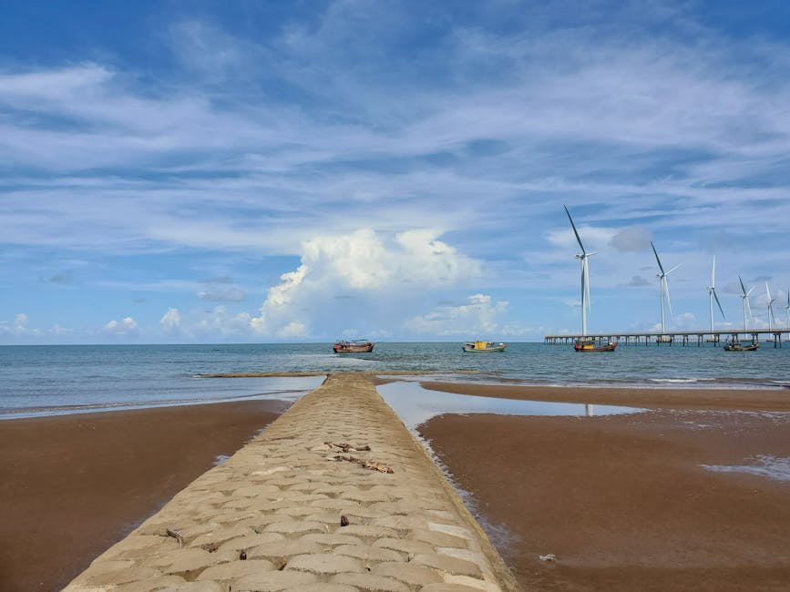 Bãi biển tuyệt đẹp với những tua bin gió và thuyền bè ở Vĩnh Long, Việt Nam dưới bầu trời xanh trong vắt.