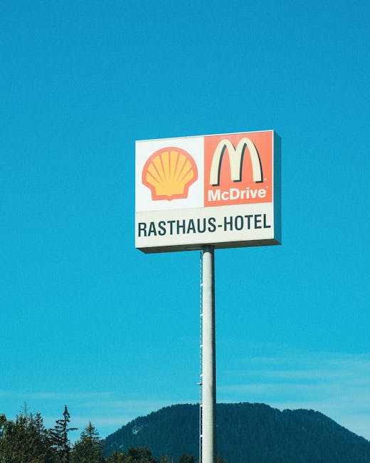 Biển hiệu khách sạn Rasthaus với logo của Shell và McDonald's nổi bật trên nền trời trong xanh.