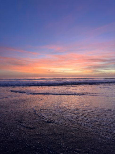 Cảnh hoàng hôn ngoạn mục trên bãi biển Malibu với những màu sắc sống động phản chiếu trên sóng biển.